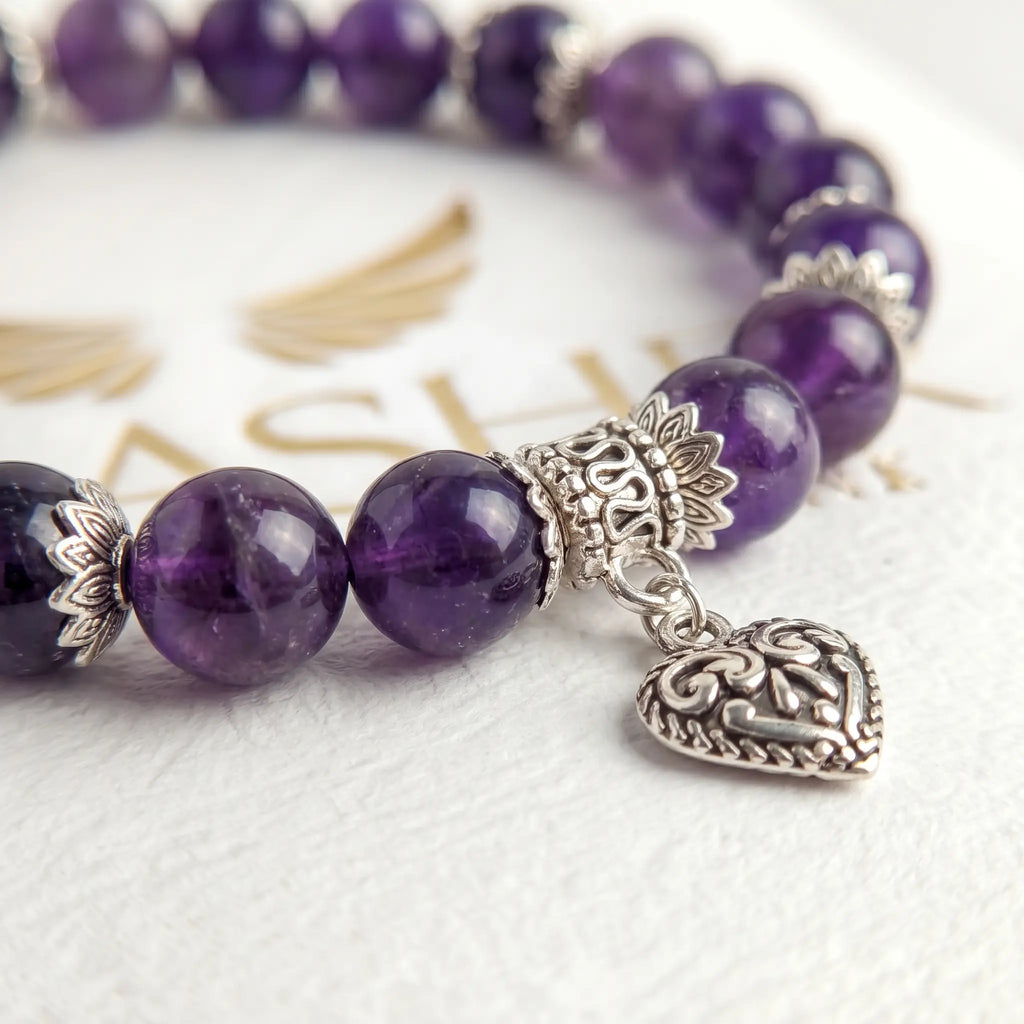 Close-up of amethyst bead bracelet with sterling silver heart charm detail