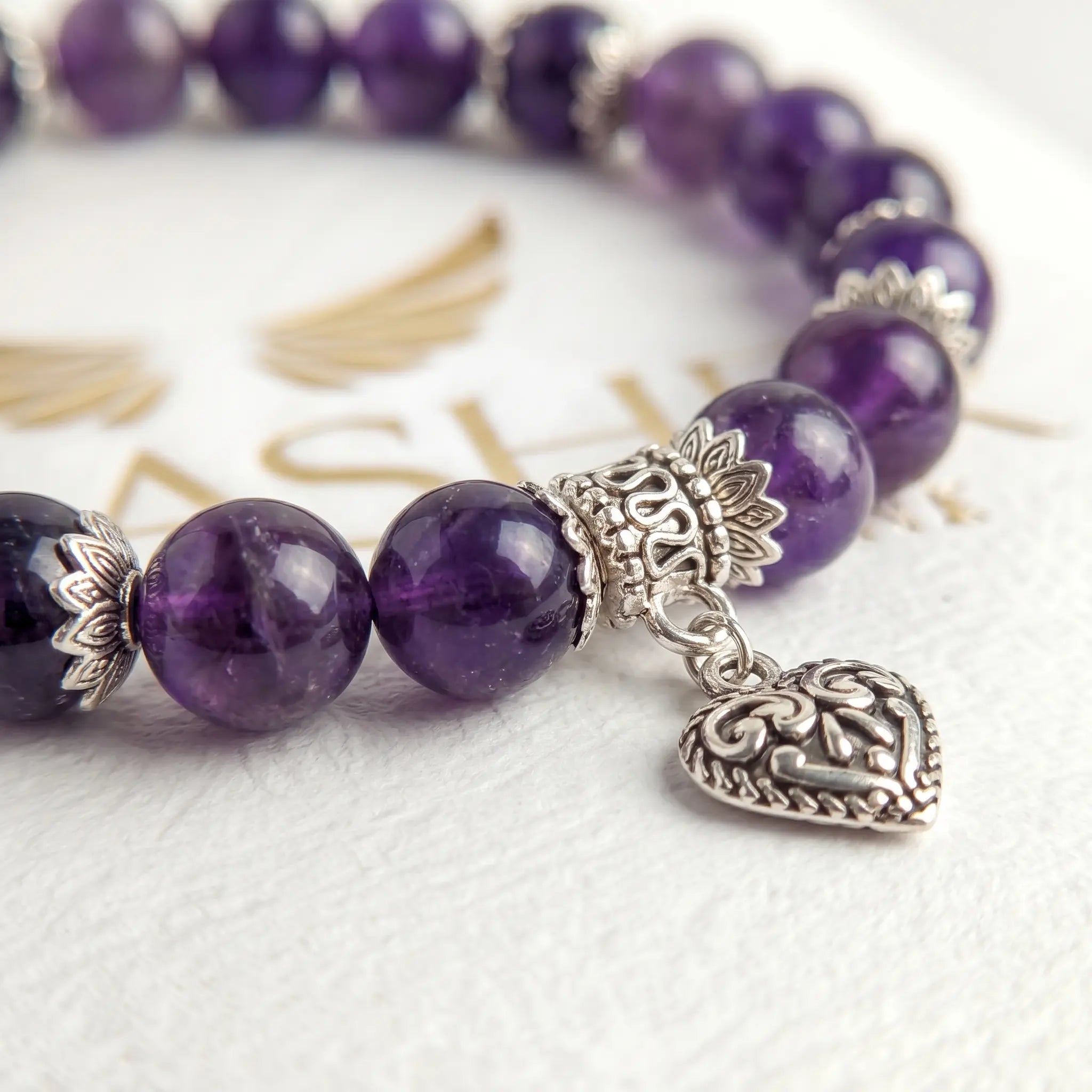 Close-up of amethyst bead bracelet with sterling silver heart charm detail