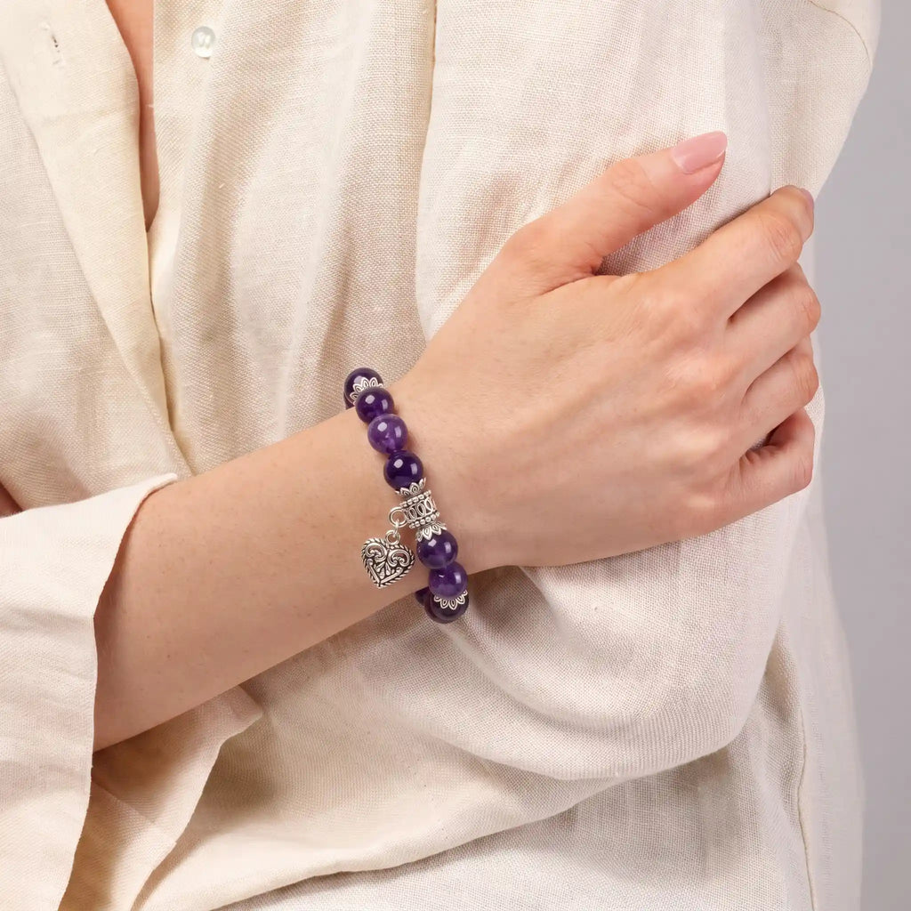 Amethyst heart charm bracelet worn on woman's wrist — gemstone bracelet for calm and clarity