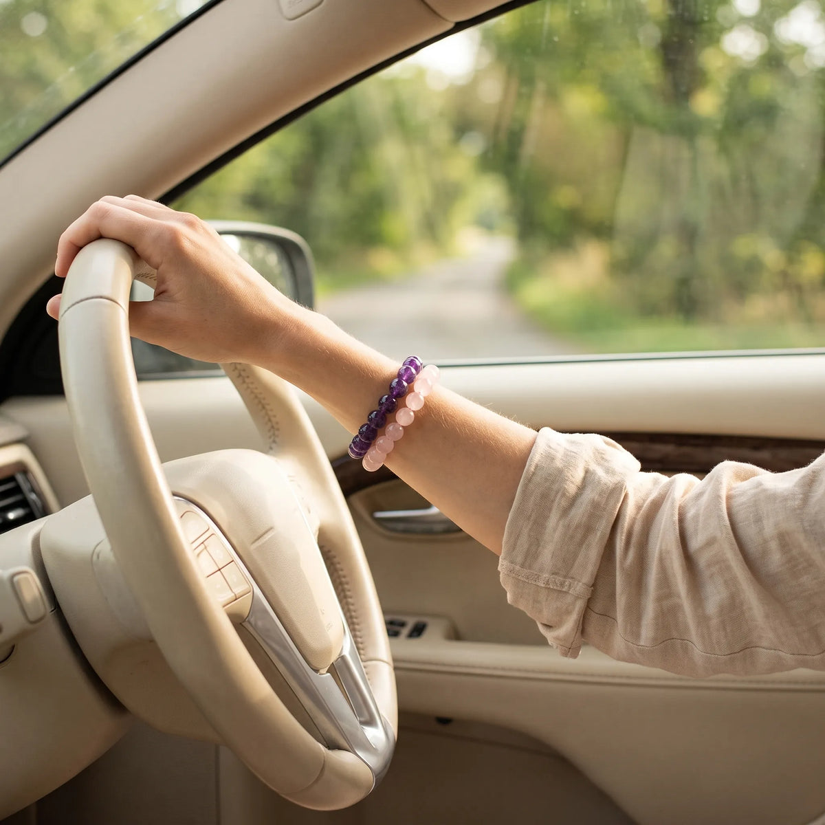 Kaashir amethyst and rose quartz bracelets stacked on a wrist while driving