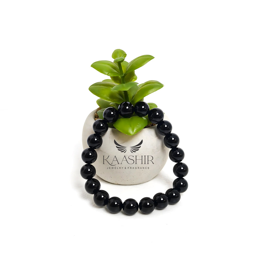A black obsidian bracelet resting on a sage smudge stick, emphasizing its metaphysical properties.