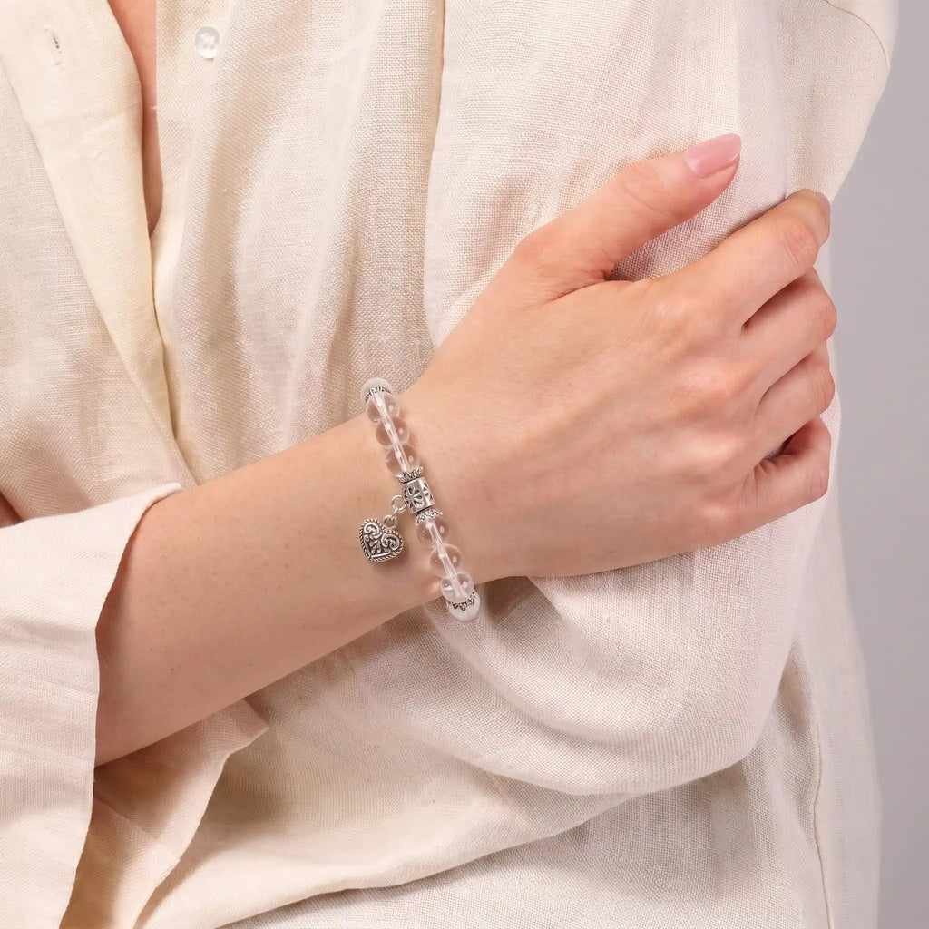 Clear quartz heart charm bracelet worn on woman's wrist — crystal for clarity and focus