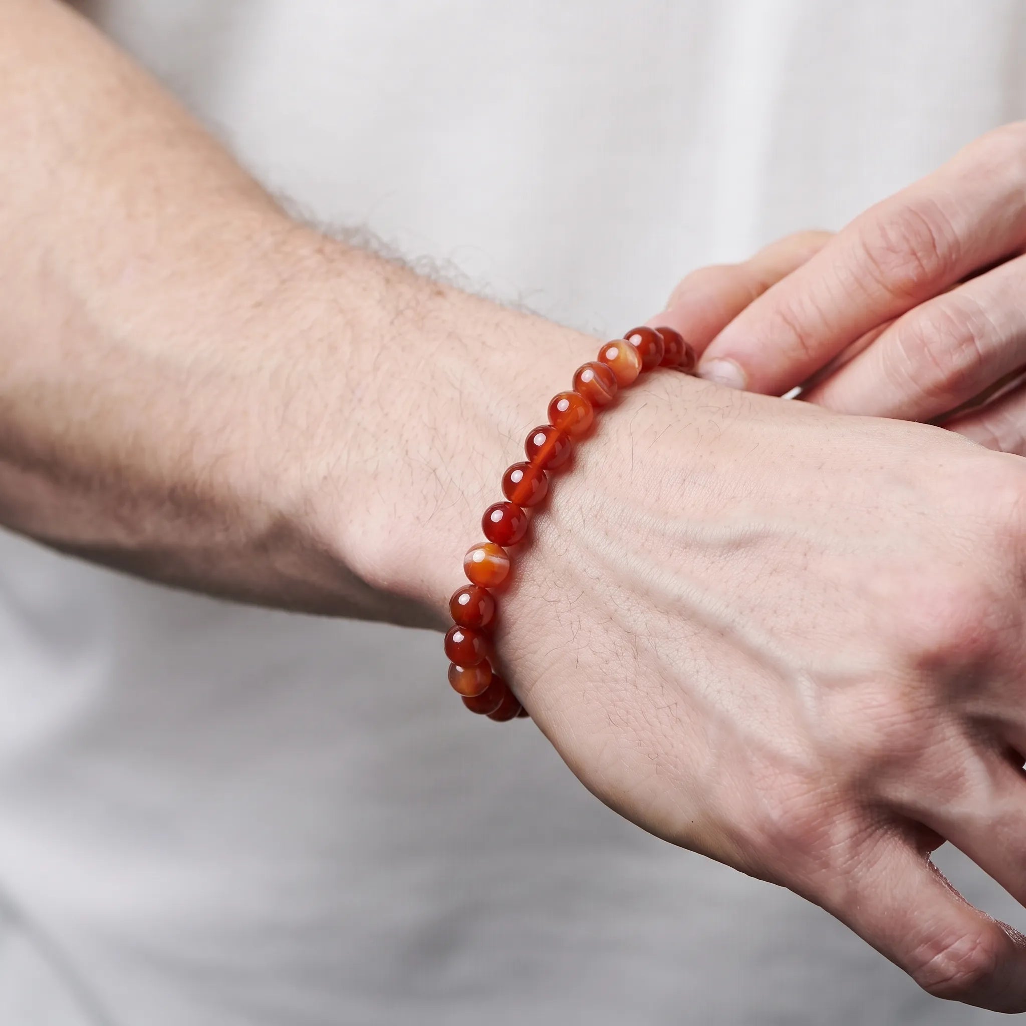 Man wearing a red banded agate bracelet - unisex grounding gemstone bracelet
