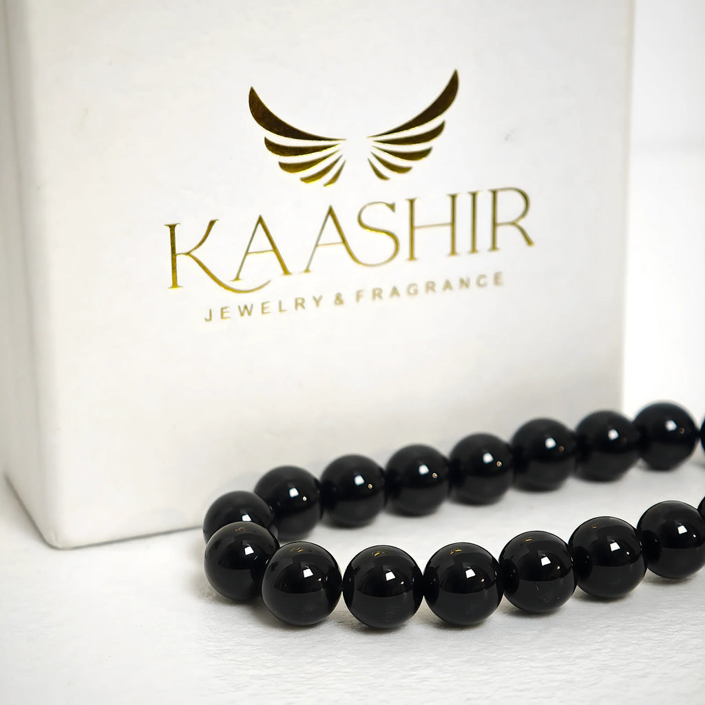 Close-up of genuine black obsidian beads showing the volcanic glass luster and smooth surface.