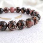 Close-up of genuine rhodonite bracelet beads showing natural pink and black pattern