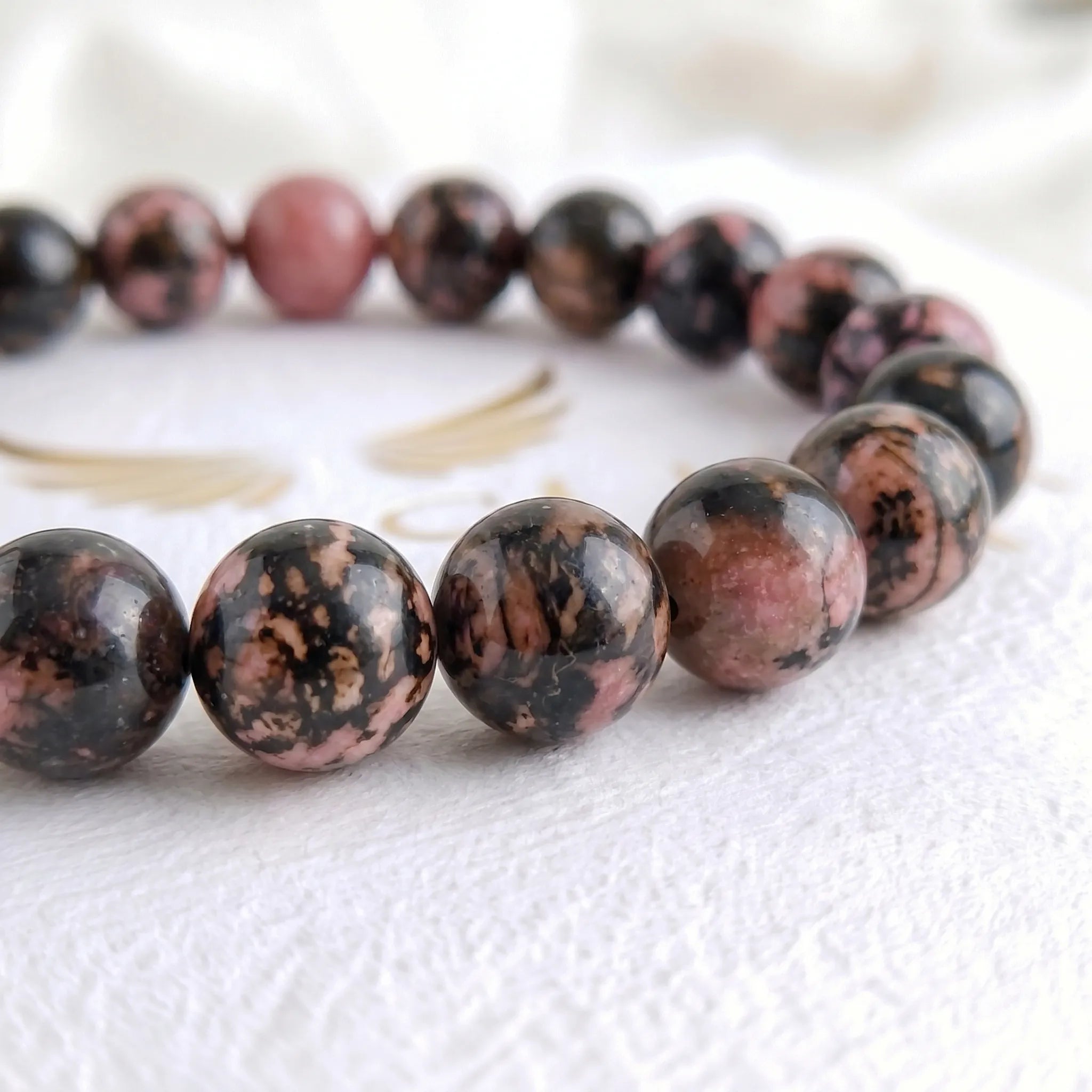 Close-up of genuine rhodonite bracelet beads showing natural pink and black pattern
