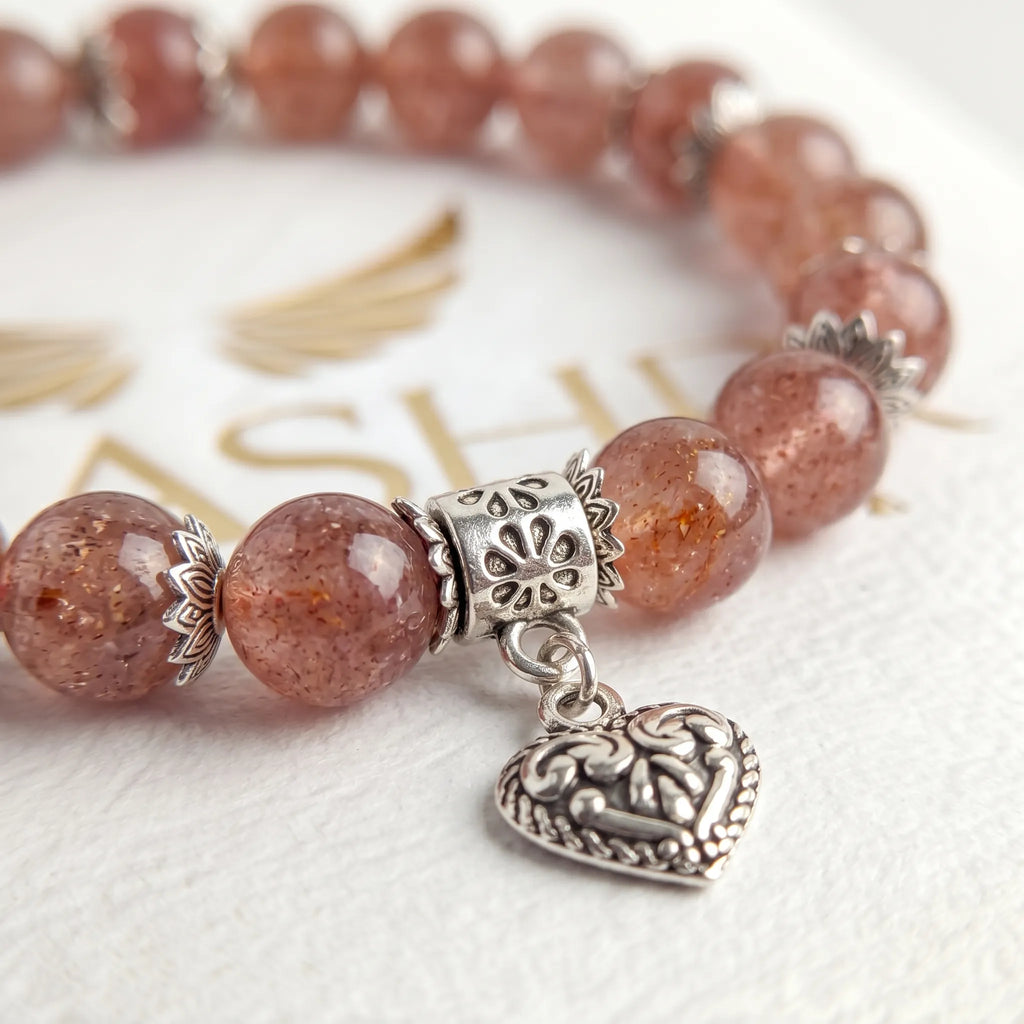 Close-up of genuine strawberry quartz bracelet with sterling silver ornate heart charm detail