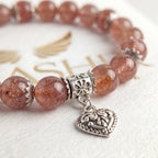 Close-up of genuine strawberry quartz bracelet with sterling silver ornate heart charm detail