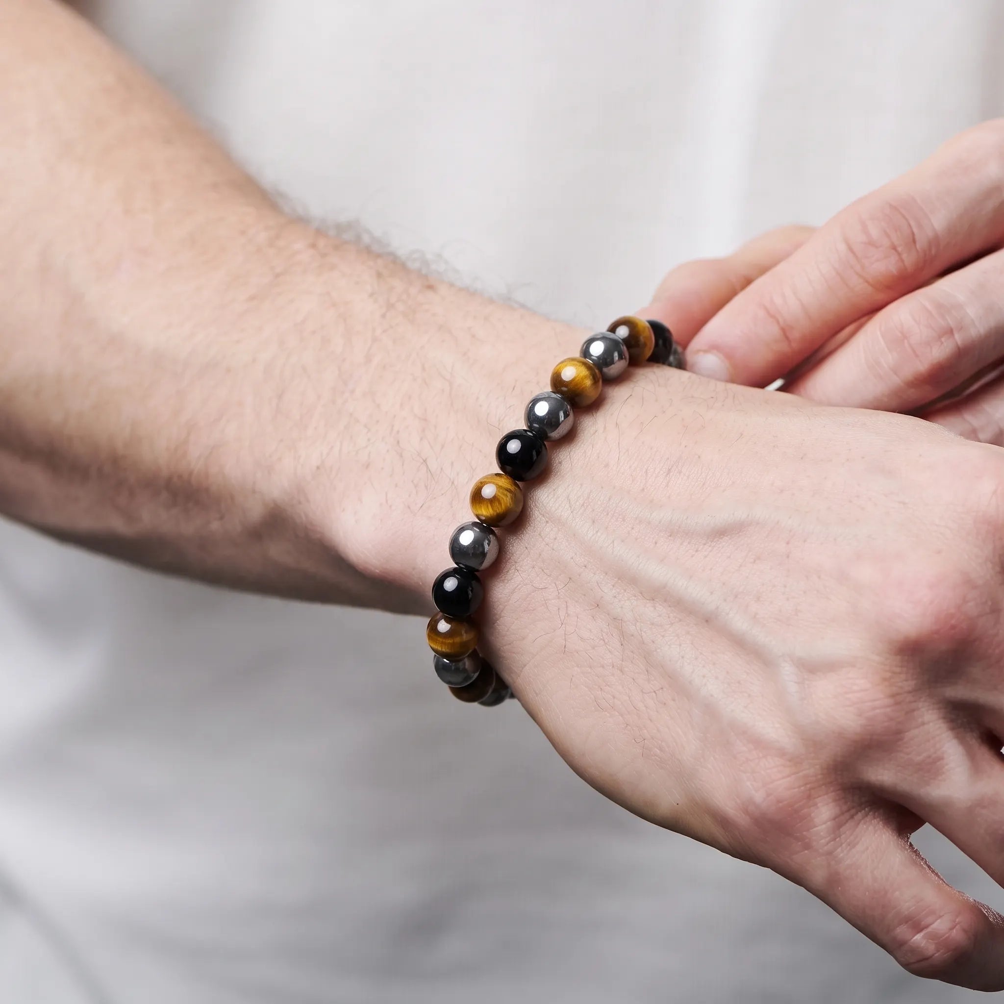 Triple protection bracelet worn on wrist showing tiger eye and obsidian beads