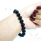 A person wearing a black obsidian gemstone bracelet for spiritual protection and grounding.